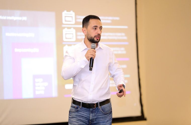 Salem Ababneh speaking with a microphone in front of a projected slide showing how machine learning and deep learning sit inside artificial intelligence.
